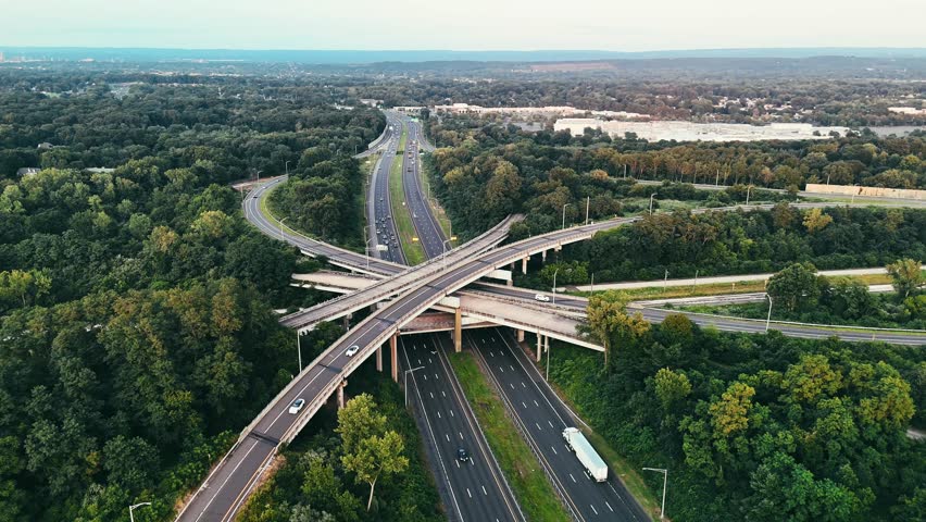 Aerial view of Connecticut highway interchange with traffic through green forest, representing transportation infrastructure, commuting, mobility, and regional connectivity.