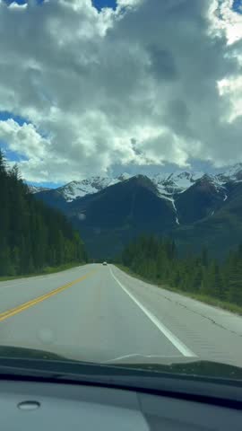 Beautiful nature in the Banff National Park. British Columbia, Canada. Scenic view of a highway surrounded by mountains and trees under a cloudy sky