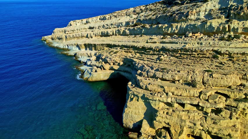Aerial view of the rugged limestone cliffs and sea caves along the coast of Crete, Greece.