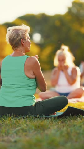 Senior women meditating during outdoor yoga class