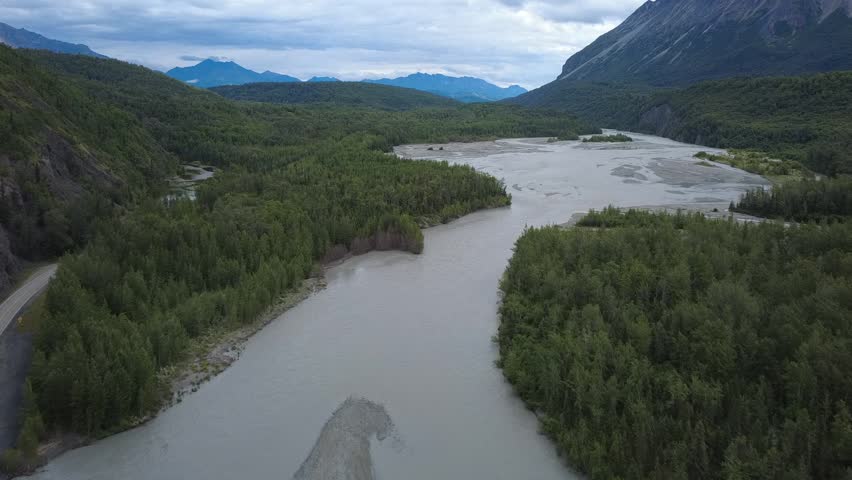 Beautiful glacial runoff from Matanuska Glacier flowing into the Matanuska River along the Glenn Highway in Alaska, featuring braided channels, turquoise water, and dramatic mountain scenery.