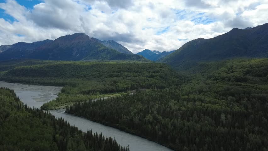 A scenic view of the Matanuska River flowing through the rugged wilderness of Alaska, showcasing turquoise glacial water, expansive landscapes, and the natural beauty of the Last Frontier.