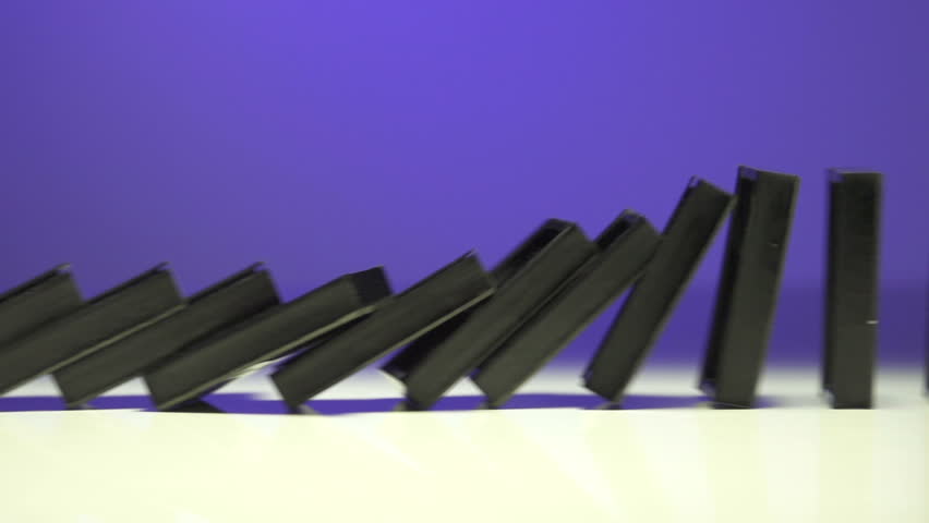 row of dominoes with one falling over on white background