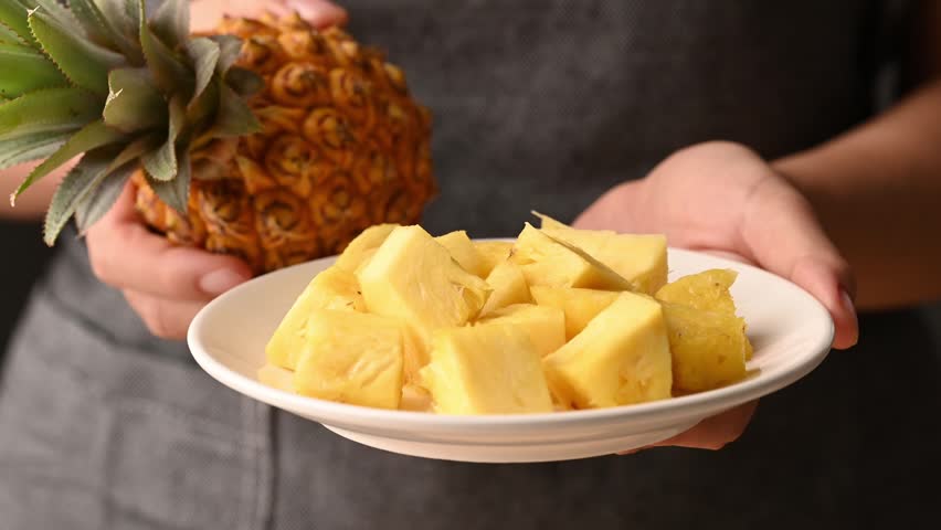 Close up of woman hands holding plate of sliced pineapple and fresh pineapple, Healthy eating concept