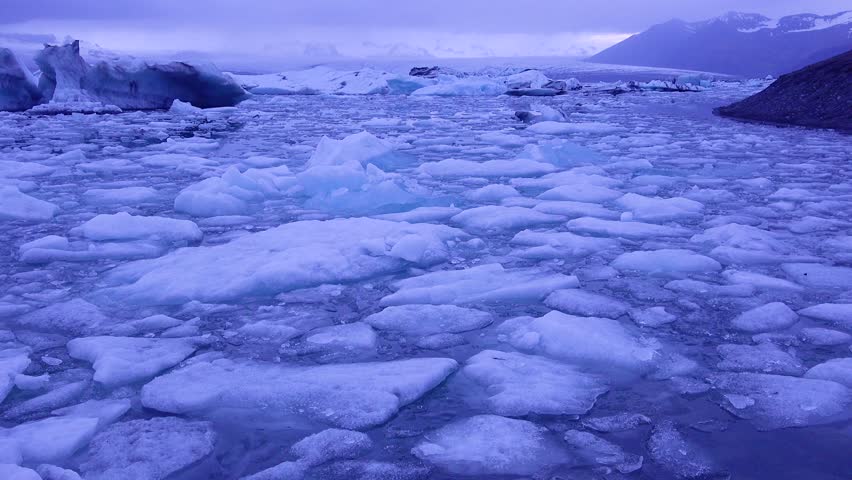 Glacier lagoon with icebergs moving slowly on the water at sunset.