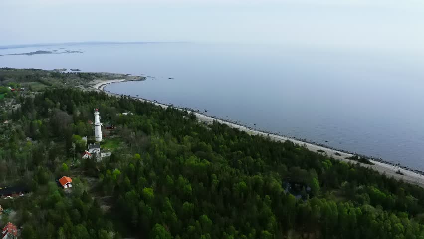 Aerial view of lighthouse on forested peninsula surrounded by water