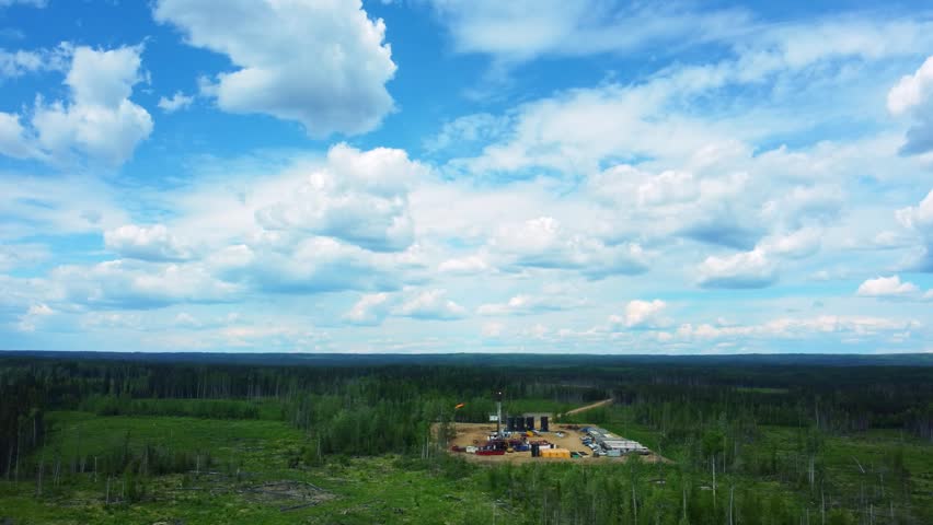 Aerial View of a Drilling Rig in a Green Field Under a Blue Sky with White Clouds, Alberta, Canada