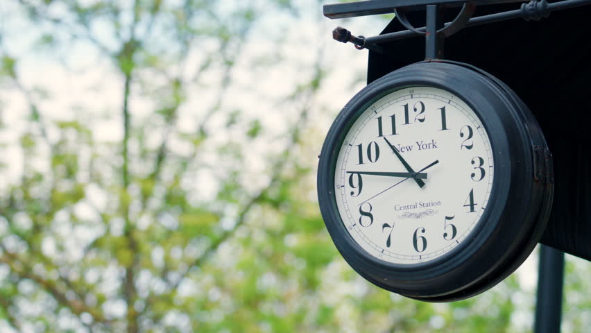 Classic outdoor clock with New York inscription, captured in soft daylight with a blurred background