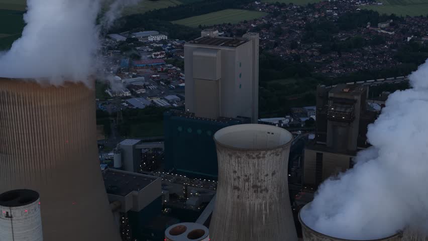 Aerial view of Power Plant Niederausem in Germany at dusk, showing a massive fossil fuel station with smoking cooling towers and industrial energy infrastructure.