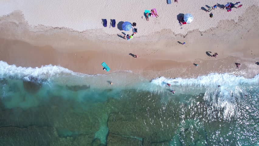 Aerial drone of a peaceful beach in Thassos, Greece, featuring transparent turquoise water, paddleboards, swimmers and a beautiful Mediterranean coastline.