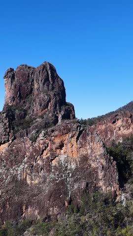 Static wide shot of craggy volcanic peaks under clear blue sky in Warrumbungle National Park.