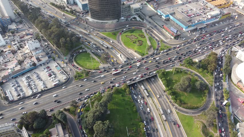 Aerial view of the busy Avenida Javier Prado Este highway interchange with heavy traffic and surrounding green spaces in San Isidro, Lima Province, Peru.