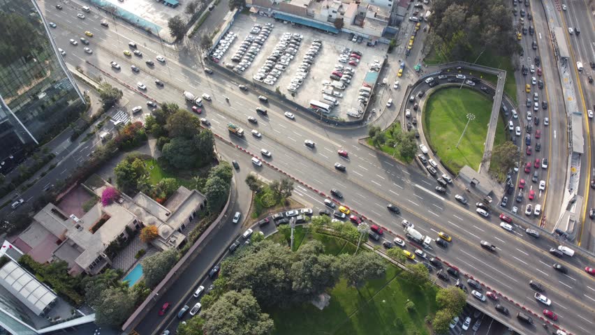 Aerial view of heavy traffic on Avenida Javier Prado Este with surrounding urban buildings, parking lots, and green spaces in San Isidro, Lima Province, Peru.