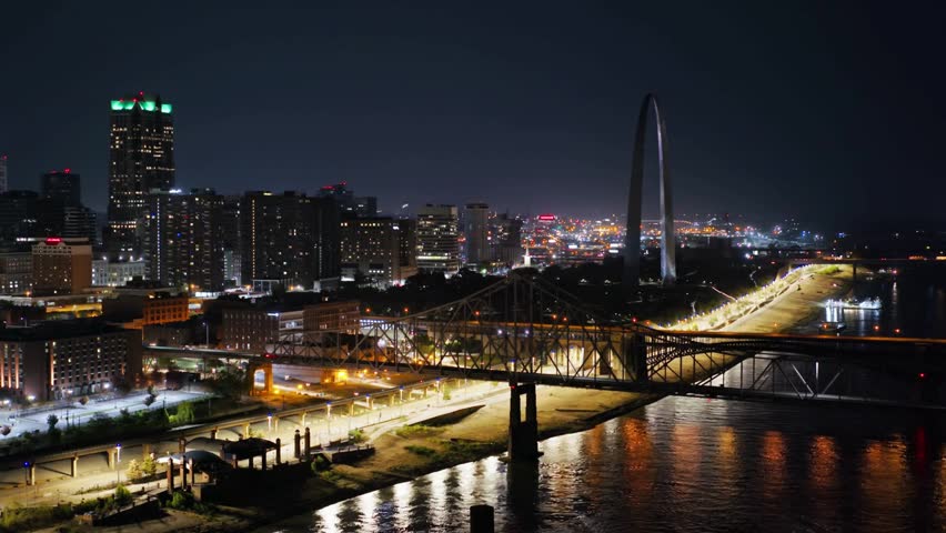 Nighttime cityscape featuring illuminated bridge and modern skyline along river