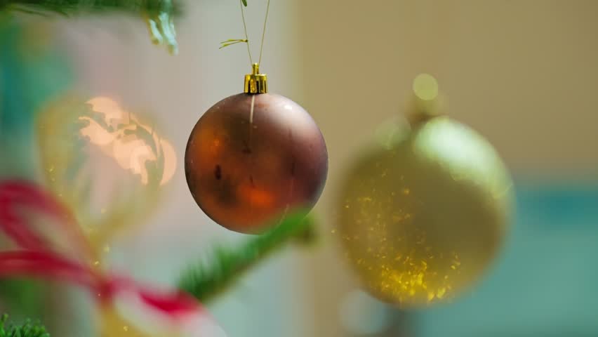 Focus shifts from red bauble to golden ornament reflecting warm Christmas lights