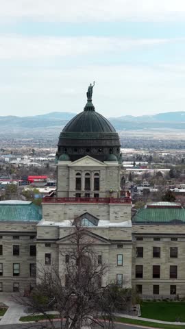 Montana State Capitol building in Helena, Montana, featuring historic dome architecture and government district surroundings. Aerial drone vertical shot. Cloudy day in american town.