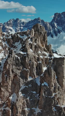 Aerial around view of majestic rocky mountains in snow Alps, Dolomites, Italy. Vertical video 4k
