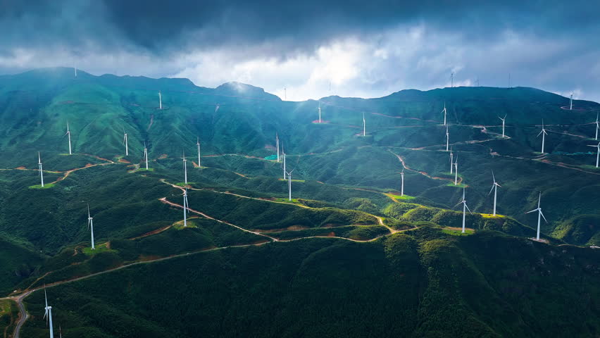 Wind turbines generation clean renewable energy on green mountain ridge under cloudy sky in Guilin, China.