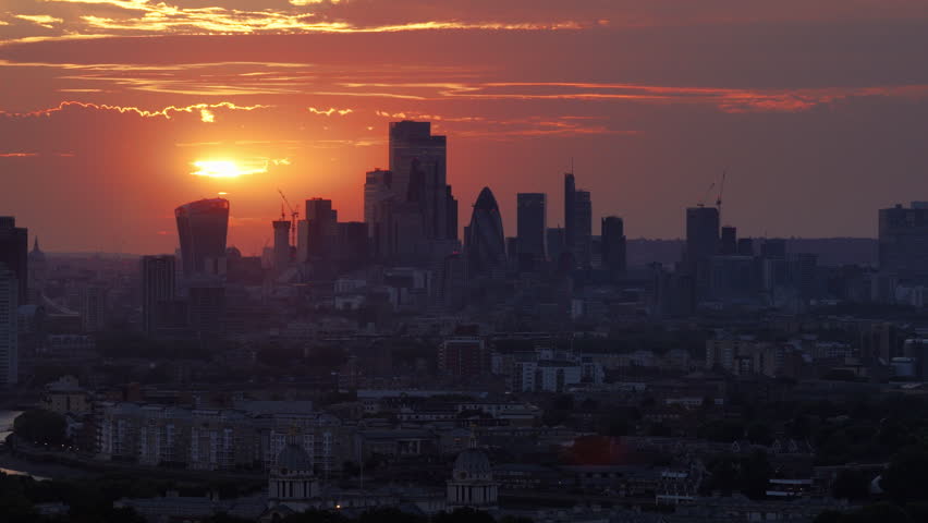 Aerial view of the London skyline at sunset featuring the City of London financial district with iconic skyscrapers, dramatic clouds and warm evening light over the British capital