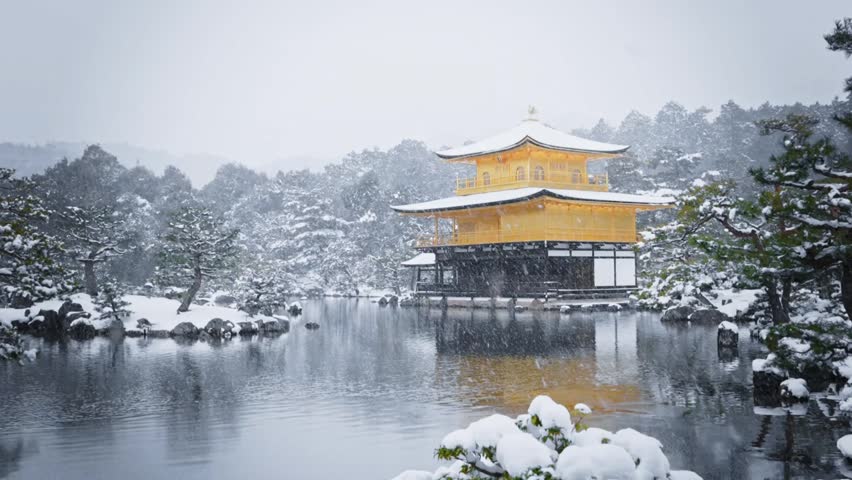 Beautiful winter view of the Golden Pavilion surrounded by snow, reflecting on a calm lake. Peaceful Japanese temple landscape with snowy trees and serene atmosphere.