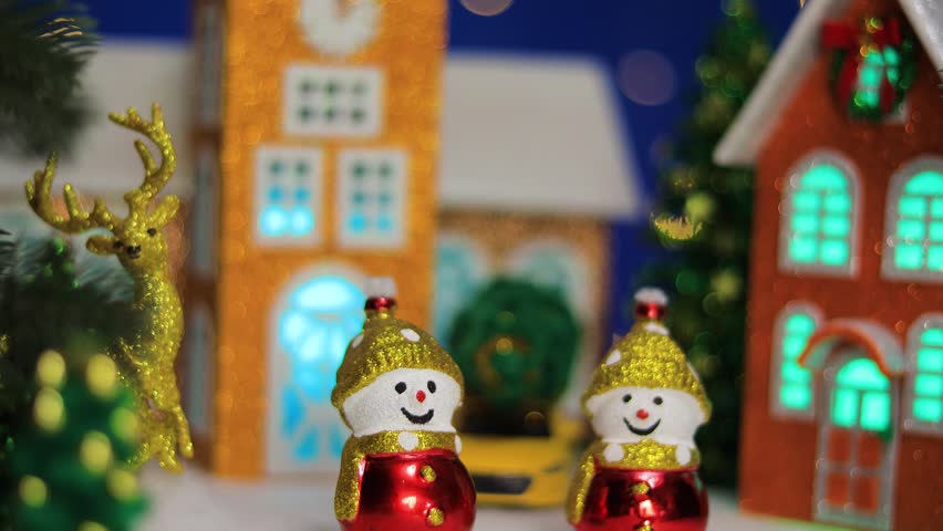 Two snowmen and Santa Claus in front of Christmas houses in Christmas town