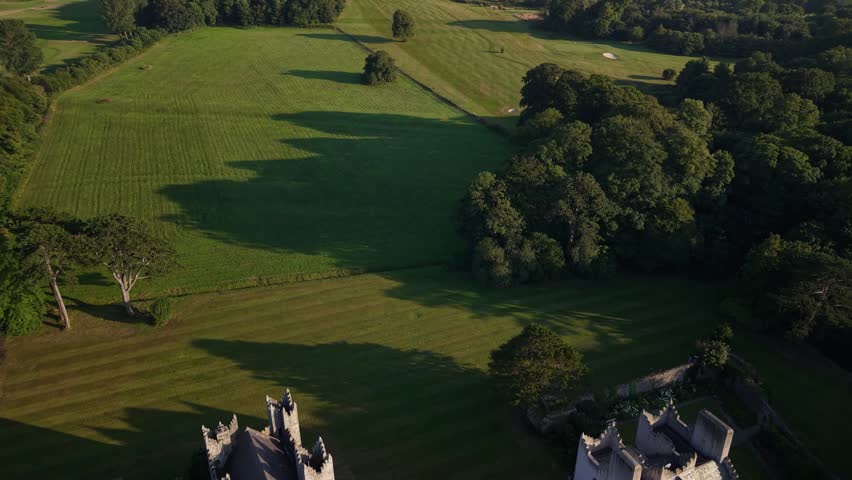 Scenic aerial reveal of Howth Castle in warm sunset light near Dublin, Ireland