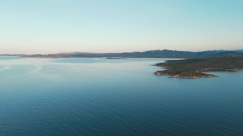 Aerial view of calm blue sea and rugged coastline at sunrise, Sardinia, Italy