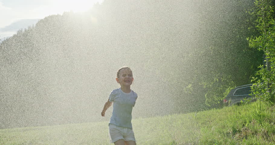 Young girl having fun jumping and dancing in the rain on a sunny day in the mountains