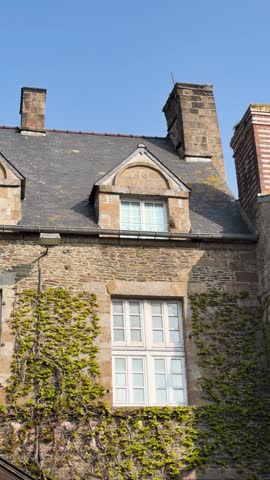 Classic French stone building in Pontorson, Normandy, with ivy on walls and slate roof