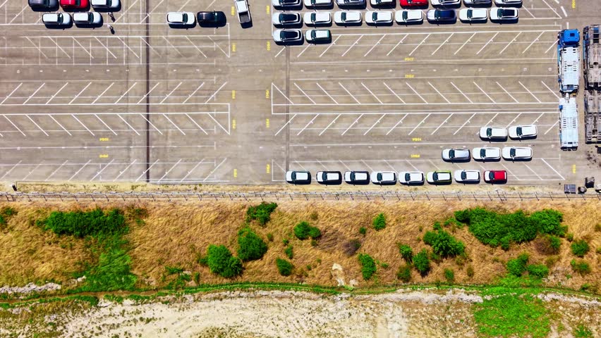 Cars parked in a lot on a sunny day. Many cars are lined up and parked in rows at a lot during bright daylight.