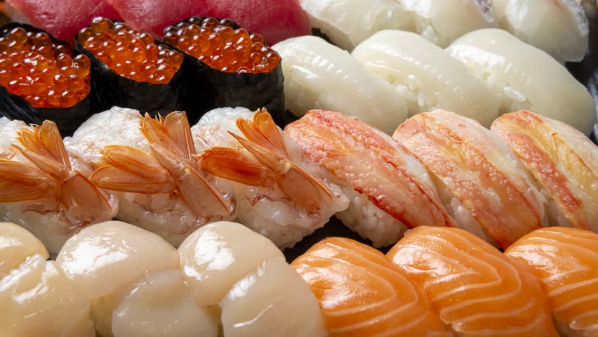 Fresh assorted nigiri sushi with ikura, scallop, shrimp, and salmon arranged on white rice for takeout service