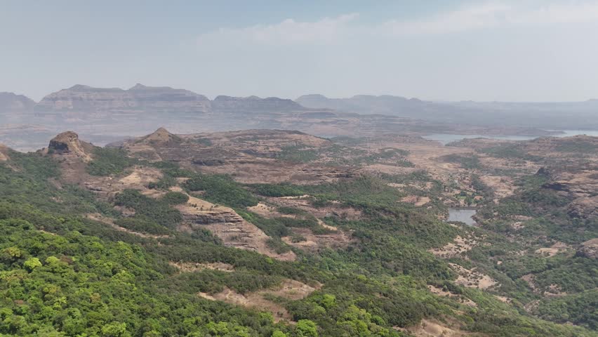 Aerial view over forested Sahyadri hills and rocky valleys near Ratangad and Bhandardara in Maharashtra India.