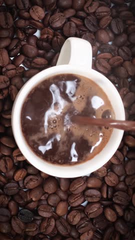 vertical shot of pouring Turkish coffee into cup on coffee beans