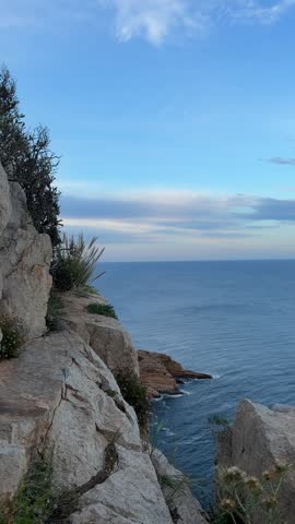 Vertical shot from the edge of a high cliff looking down at the deep blue Mediterranean water washing against rocky headlands at Cabo de la Nao in Alicante, Spain.