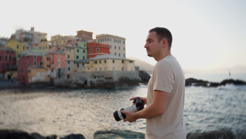 Man photographing colorful seaside buildings at sunset in an Italian coastal village