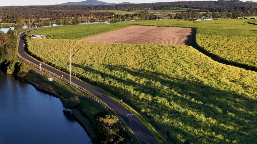 High-angle drone shot of agricultural fields and river during golden hour in New South Wales.