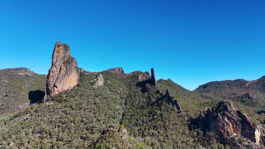 Wide aerial shot of volcanic rock formations under clear blue skies in Warrumbungle National Park.