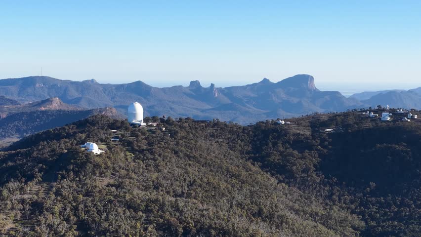 Wide shot of telescope domes on a mountain ridge in Warrumbungle National Park, Australia.