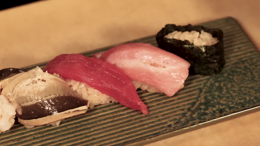 Close-up of premium tuna and sea urchin sushi served on a textured ceramic platter.