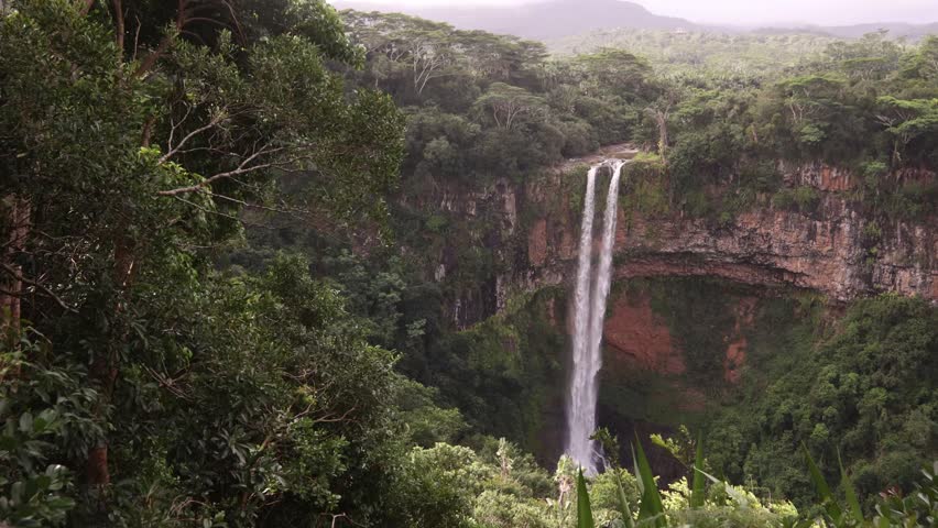 Aerial drone view capturing the tall cascade of Alexandra Falls plunging into the lush green tropical canyon of Black River Gorges National Park in Mauritius.