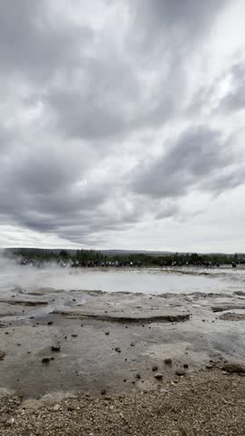 Powerful eruption of Strokkur geyser in the Haukadalur geothermal area under a dramatic cloudy sky in Iceland.