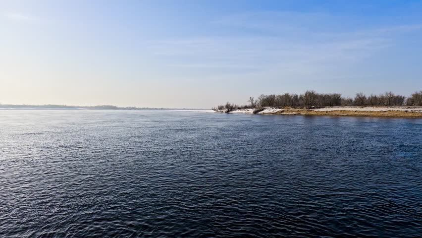 Snow river winter landscape. Frozen ice and snow by river. Spring thawed ice on water.