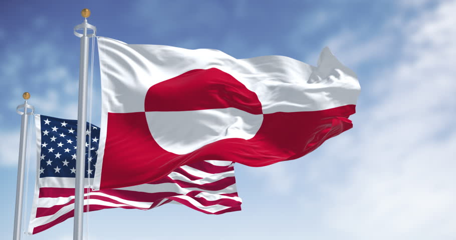 Flags of Greenland and the US waving in the wind on a clear day. Greenland is the world
