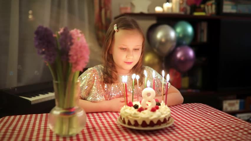Little girl blowing out birthday candles and making a wish during her eighth birthday celebration at home