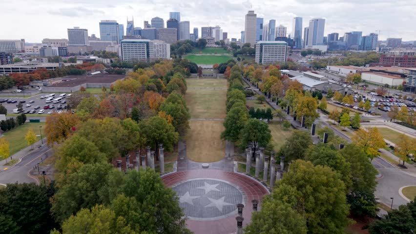 Bicentennial Capitol Mall State Park during a colorful autumn with the State Capitol Building and the Nashville, Tennessee city skyline as a backdrop, aerial flyover