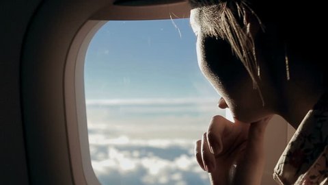Girl looks at the clouds from airplane window