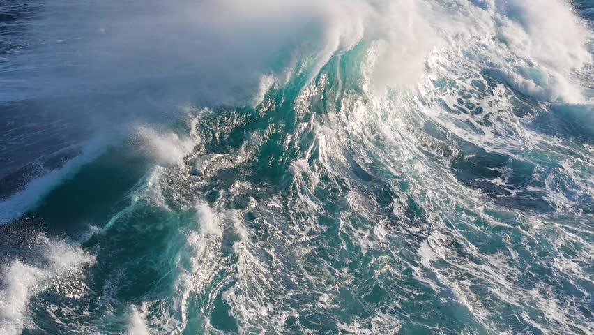 Powerful ocean wave breaking with white foam and spray in deep blue sea, massive stormy wave collapses in open ocean. Huge ocean wave crashing in stormy sea with splash and foam
