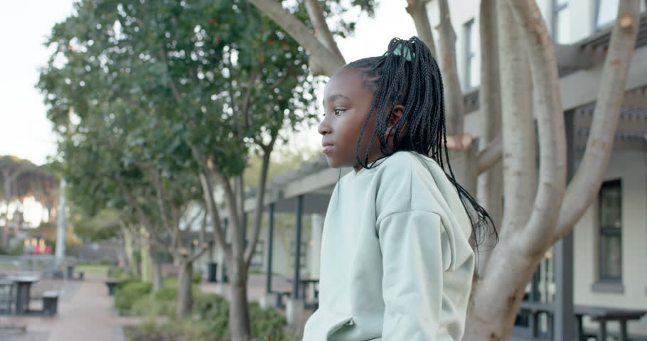African female youth turning toward camera as framing tightening, smiling in mint hoodie by tree. Campus, courtyard, exterior, portrait, casual, daylight, pathway