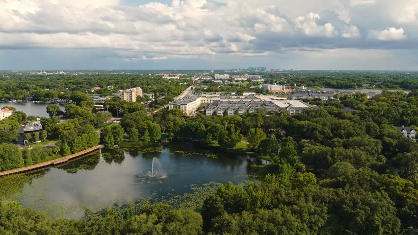 Aerial time lapse of the lakeside town and dense foliage under a dramatic cloudy sky in Maitland, Florida, USA. June 27, 2022.