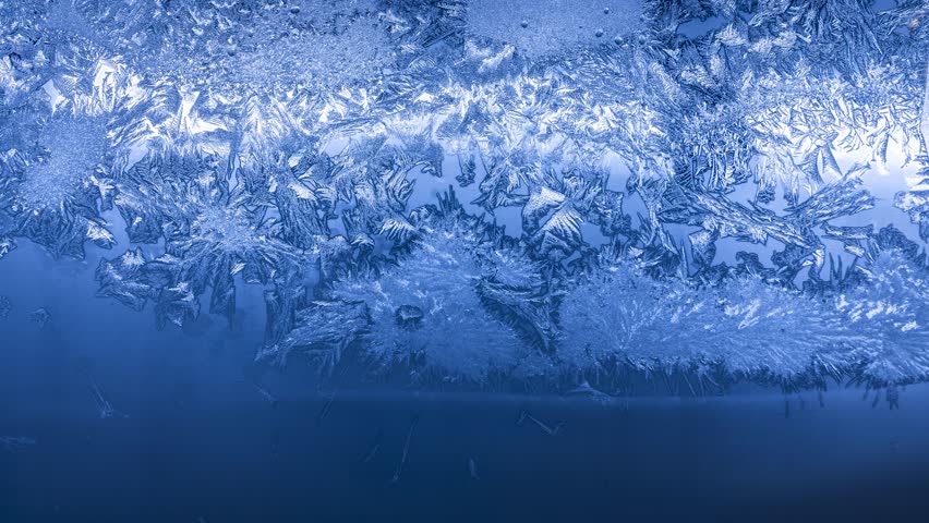 Intricate frost crystals forming delicate dendritic patterns on frozen glass during extreme winter cold weather